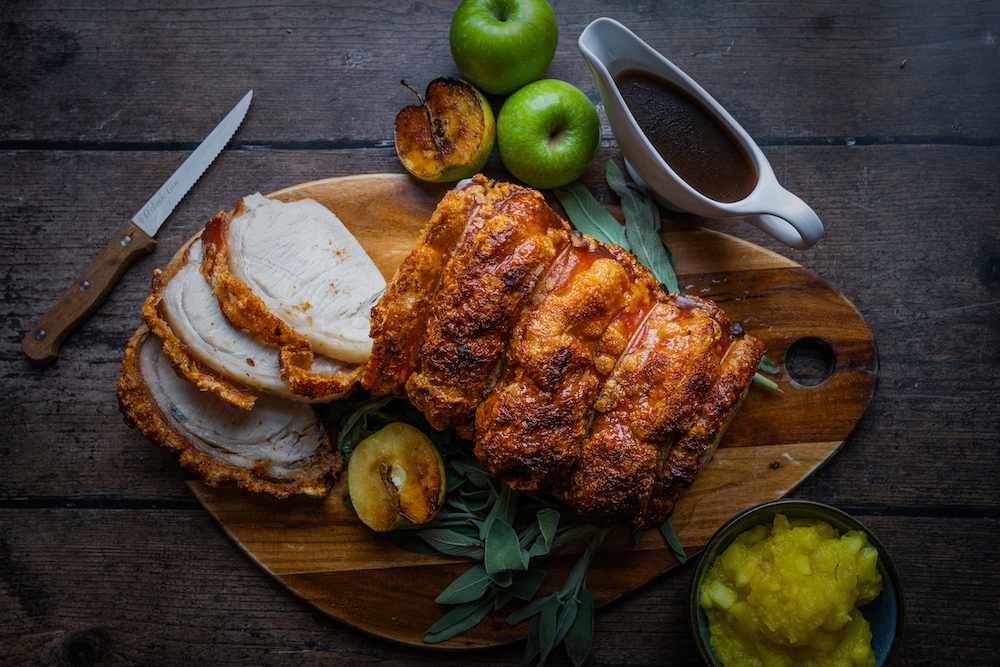 A perfectly roasted pork loin with crispy crackling, served on a wooden cutting board alongside roasted apples, fresh sage, and a jug of gravy. The juicy meat and golden crackling are sliced and ready to serve, creating an inviting and hearty meal. This traditional roast dinner is one of the standout offerings at The Square Club, a top restaurant in Clifton. Known for its refined approach to British classics, this restaurant in Bristol is a favorite among locals and visitors alike for its hearty and flavorful dishes.